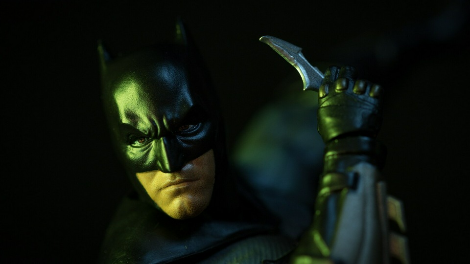 Бэтмен держит знак Летучей мыши