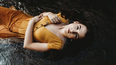 Девушка, лежащая в оранжевом платье 4k